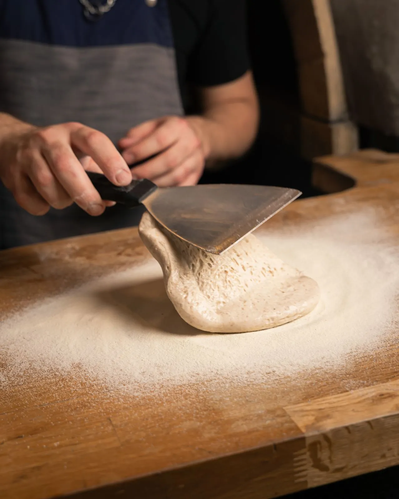 Manos formando la masa de pizza sobre mesa enharinada