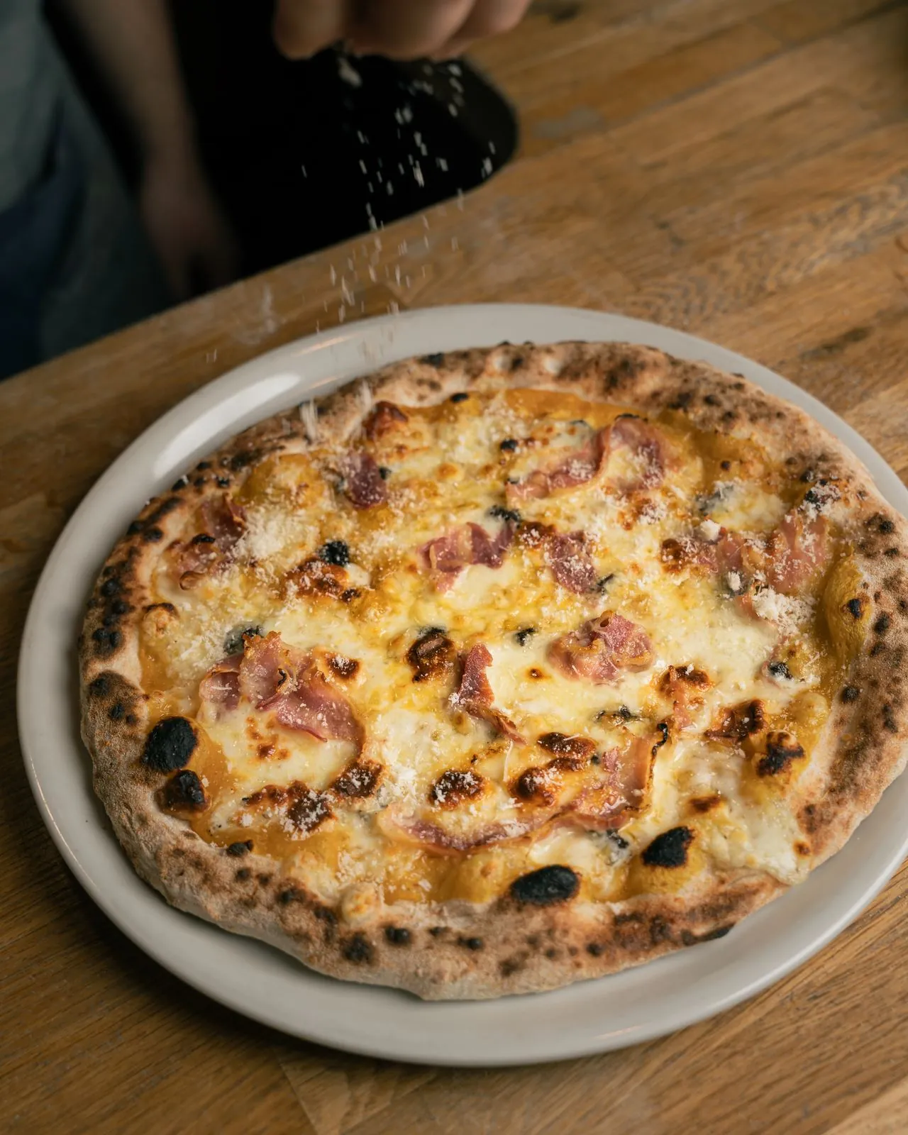 Parmesano rallado sobre pizza recién horneada